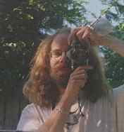 (Photo of a mirror reflecting an
image of a long-haired guy with a camera)