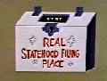 (still: Official Statehood-Petition Box, with sinister eyes peering through slot)