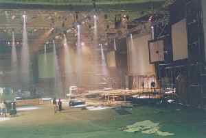 (Photo: beams of 
light shine down from the lighting trusses onto the nearly-completed 
stage)